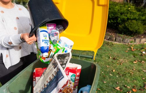 Image of loose recycling items being placed in kerbside recycling bin