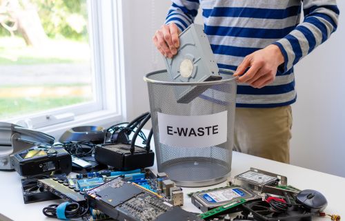 Image of someone placing electronic waste in a bin to take to the tip