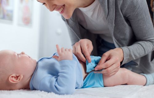 Baby being buttoned into reusable nappy 