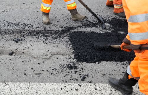 close up photo of a pothole being filled with asphalt 