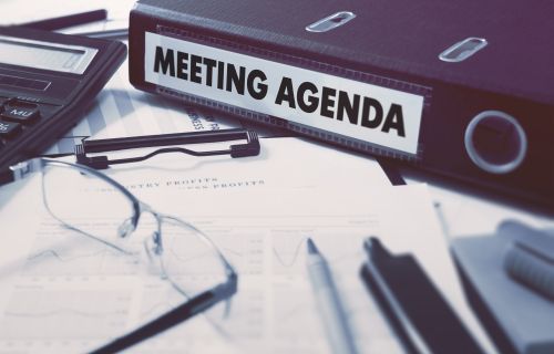 a folder with "meeting agenda" label on a messy desk
