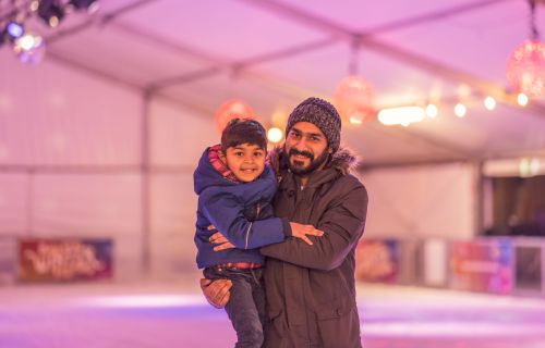 A man and a young girl enjoying the ice skating rink at Winter Festival
