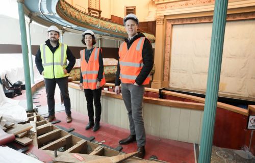 three people in high-vis vests standing in the construction site of Her Majesty's Theatre 