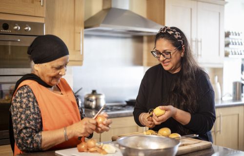 A younger and an older woman in the kitchen preparing food together.