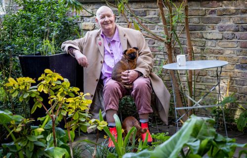Man sitting in his garden with a small dog on his lap