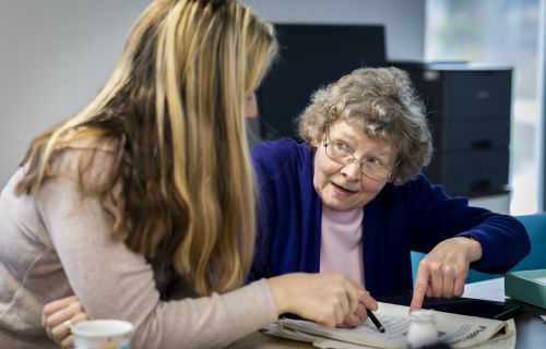 Two women sitting together reviewing a paper