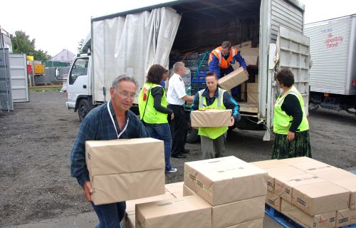 People handing out cardboard boxes from a truck after a disaster