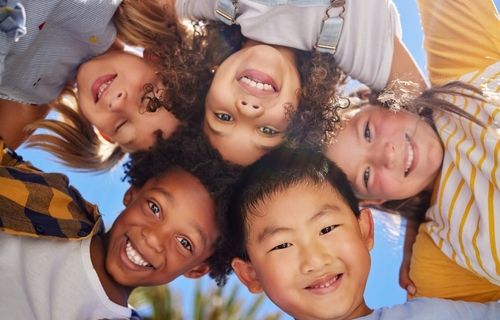 Children of many races in a circle smiling at the camera