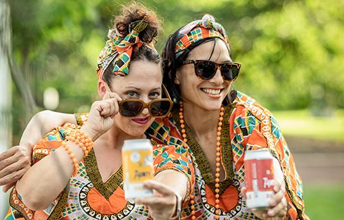 Two women with sunglasses and colourful outfits in a park