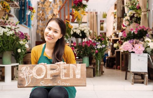 lady inside florist holding an open sign