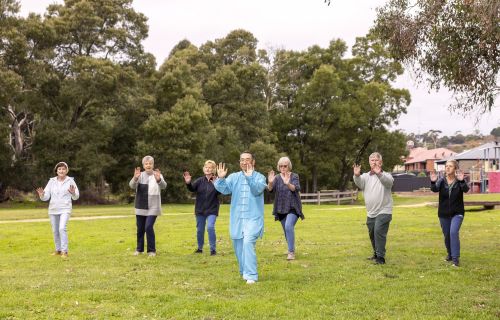 image of man leading four women and one man in a tai chi class held outdoors
