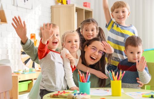 Image of kinder teacher and kids excited with hands in the air