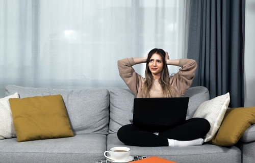 young lady sitting on a couch with her hands over her ears