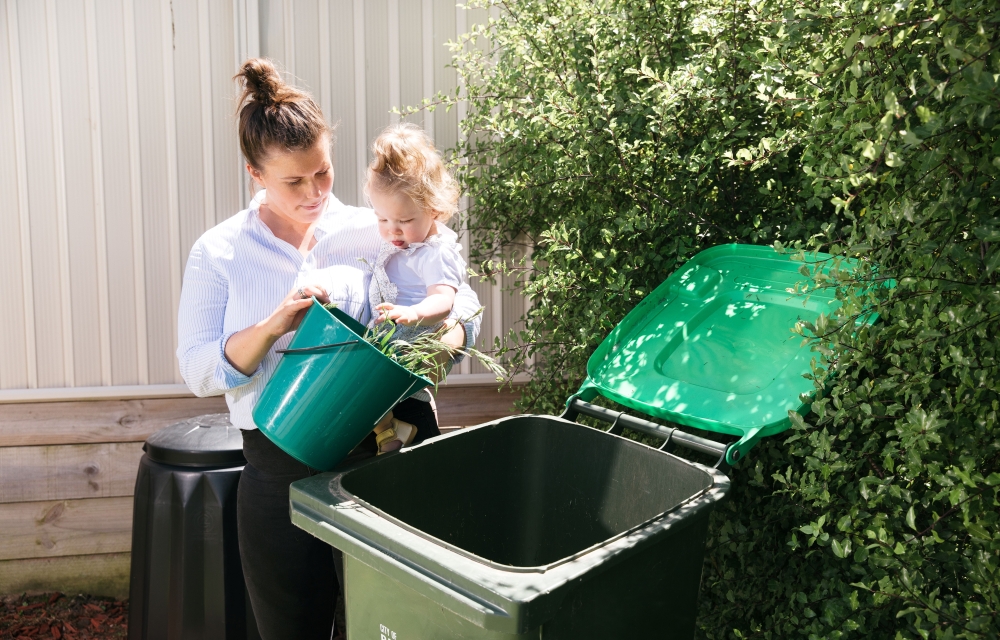 Image of mother and baby placing weeds in the kerbside green waste bin