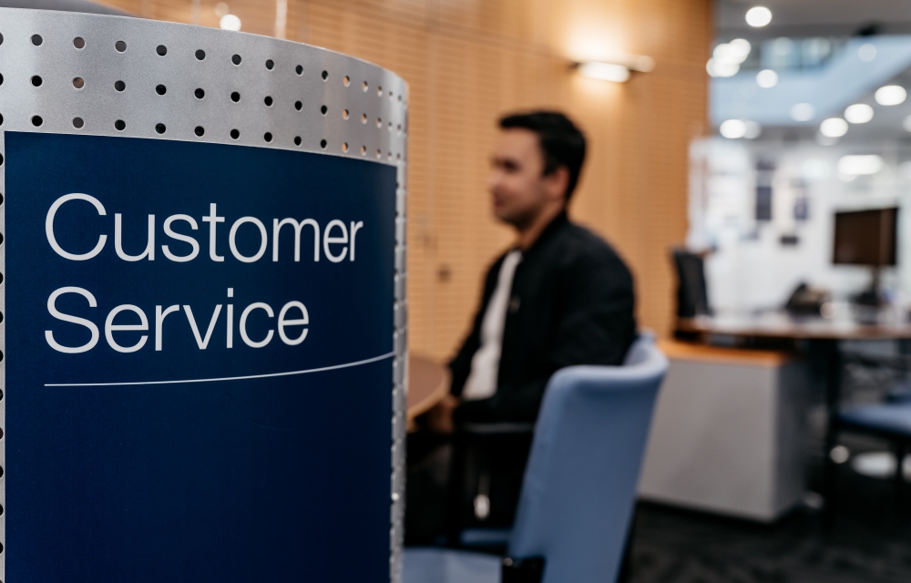 customer service sign with person sitting in the background