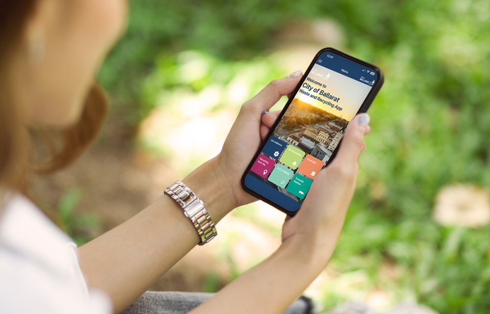 image of person outside on their phone with Ballarat Waste app on the screen