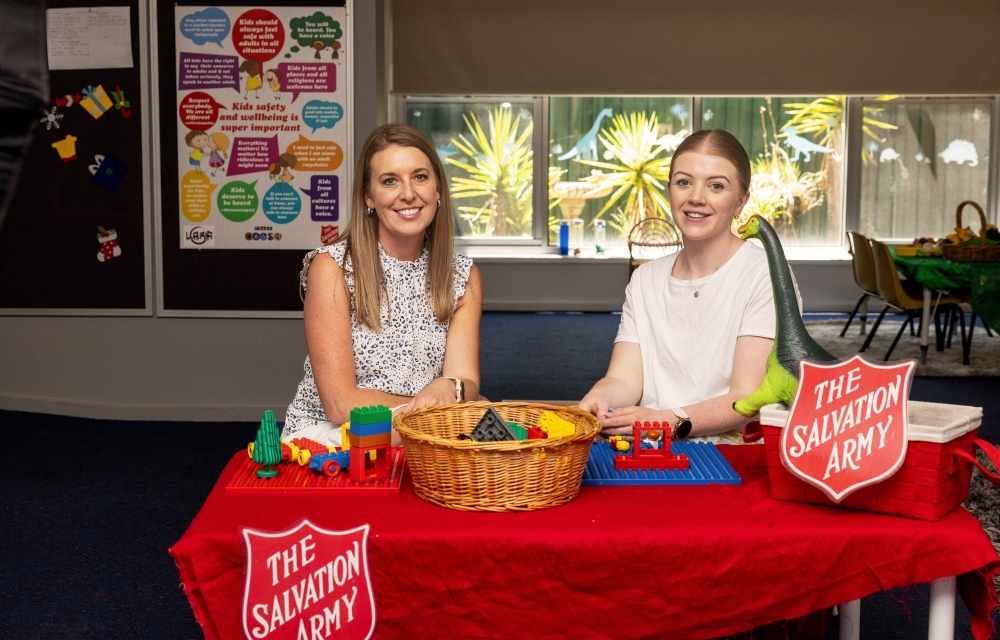 Salvation Army Karinya Support Services’ Louise Jeffrey and Tiffany Foster sit at a table with toys on it and a ‘Salvation Army’ sign.