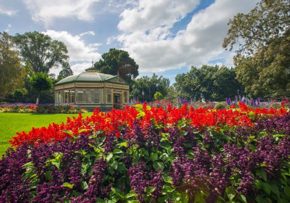 The Ballarat Botanical Gardens conservatory is the background and a garden bed full on red flowers is in the foreground.
