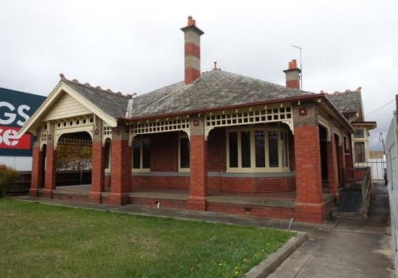 An image of Osborne House, a federation-era villa, which is located next to Bunnings. The red-brick house has a green lawn in front of it and you can see part of the 'Bunnings' sign to the left of the house.