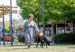 Heidi Biggin walks on a patch of grass with her guide dog Freya.