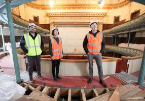 Three people in high-vis vests stand on the second tier of the Her Maj construction site