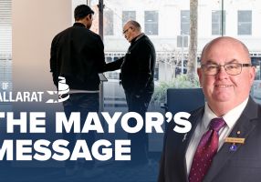 Text with The Mayor's Message with an image of Mayor Cr Des Hudson in front of a drop-in meeting