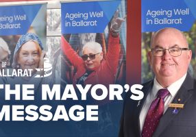 Text with The Mayor's Message with an image of Mayor Cr Des Hudson in front of Seniors Festival signage