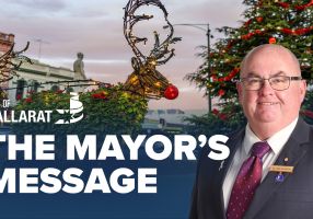 Text with The Mayor's Message with an image of Mayor Cr Des Hudson in front of the Ballarat Christmas display