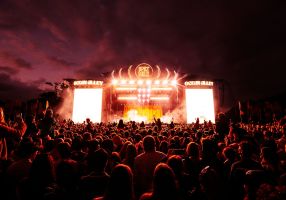 The Spilt Milk stage is lit up behind a dark night sky. 