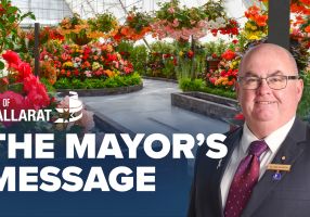 Text with The Mayor's Message with an image of Mayor Cr Des Hudson in front of the begonia display at the Botanical Gardens