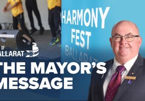 Text with The Mayor's Message with an image of Mayor Cr Des Hudson in front of the Harmony Fest stage