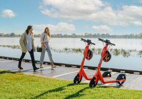 people walking by the lake with scooters parked on lakes edge