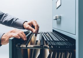 Hands flicking through a filing cabinet