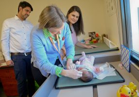 Nurse measuring baby with family