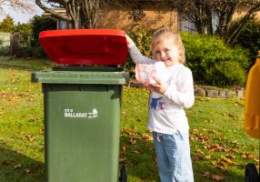 Image of a child placing rubbish in the kerbside waste bin