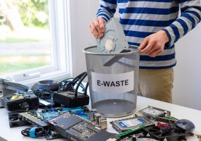Image of someone placing electronic waste in a bin to take to the tip