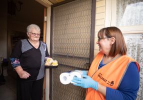 Image of a Meals on Wheels volunteer delivering toilet paper