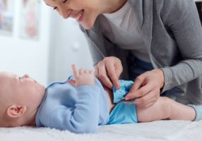 Baby being buttoned into reusable nappy 