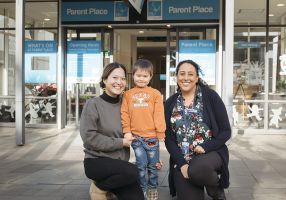Two women and a child outside the parent place building on Sturt Street