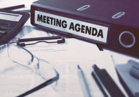 a folder with "meeting agenda" label on a messy desk