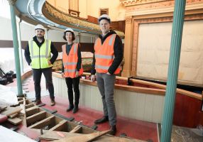 three people in high-vis vests standing in the construction site of Her Majesty's Theatre