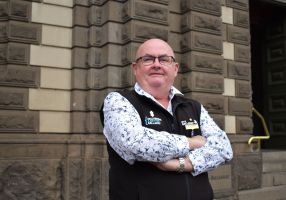 Mayor Dr Des Hudson poses with arms crossed in front of town hall