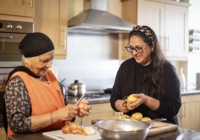 A younger and an older woman in the kitchen preparing food together.