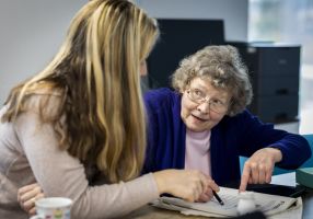 Two women sitting together reviewing a paper