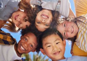Children of many races in a circle smiling at the camera